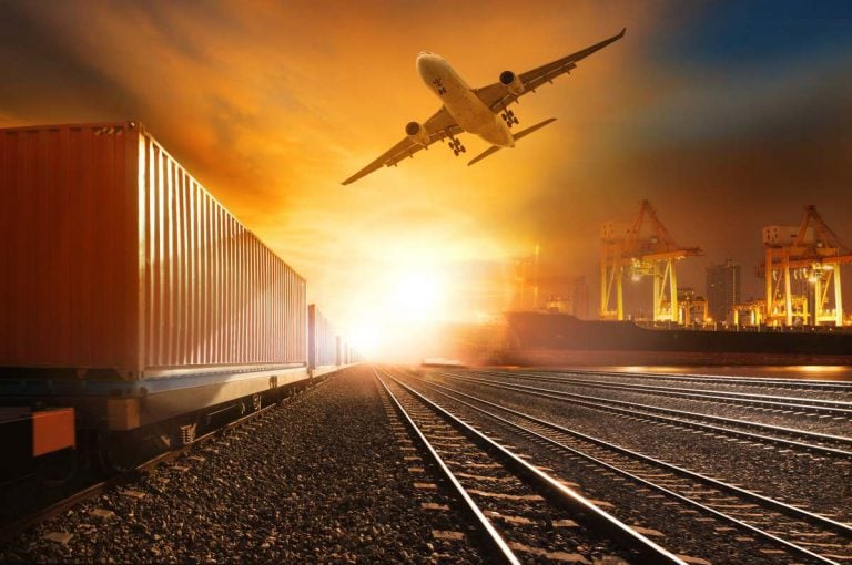 Et fragtfly overflyver containere og kraner i et ADR-farligt gods område ved solnedgang-et tydeligt billede på transport- og sikkerhedsprocedurer.