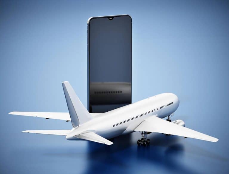 Et modelfly er placeret foran en stor smartphone på en blå baggrund, som symboliserer IATA-vejledninger for lithiumbatterier.