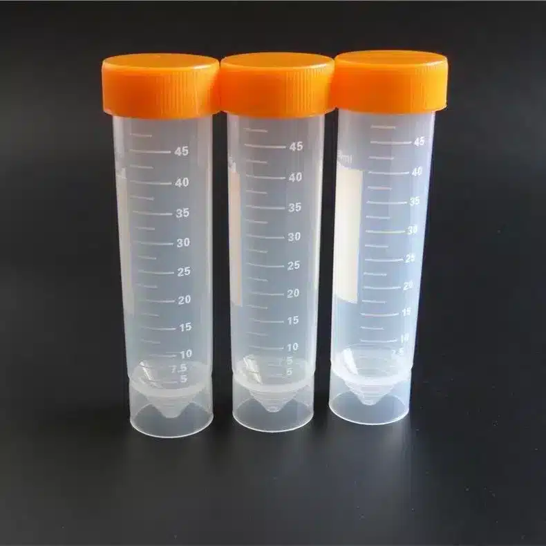 Tre plastrør med orange skruelåg fra »Prøverør, plast med skruelåg 50 ml (50 stk.)« står oprejst på en sort baggrund.