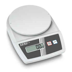 En Kern bordvægt EMB 6000-1 (6 kg / 0,1 g) viser 0,0 g på LCD-skærmen, hvor knapperne ON/TARE og OFF er synlige.